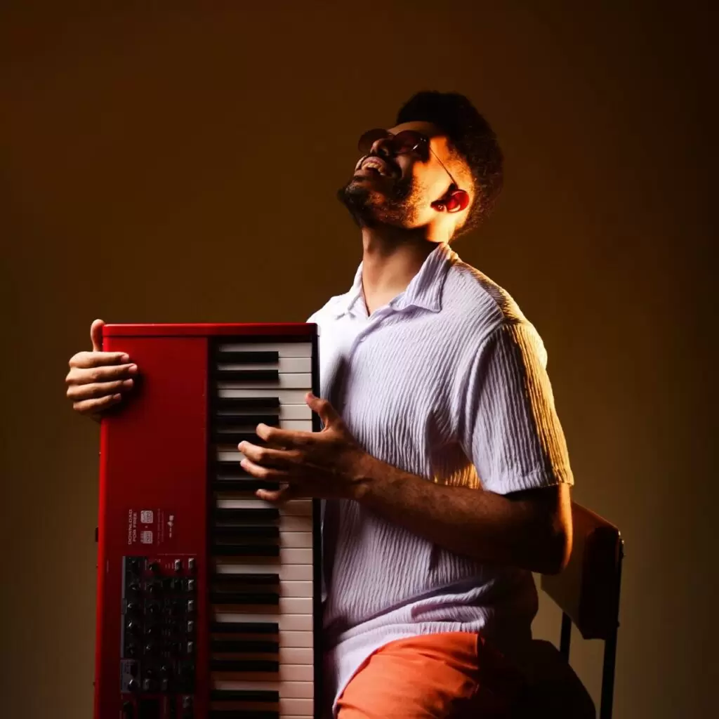 Henrique Mota ao piano, com iluminação intimista, capturando sua expressão durante um momento de improvisação.