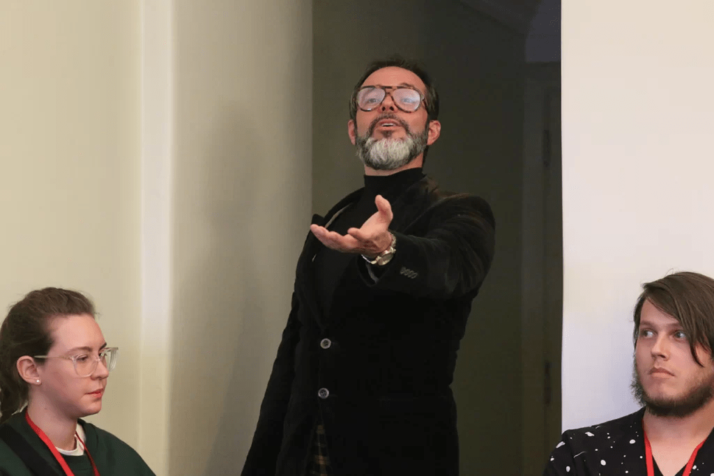 Cena do espetáculo imersivo “Traição”, com atores interagindo em ambiente anos 1960